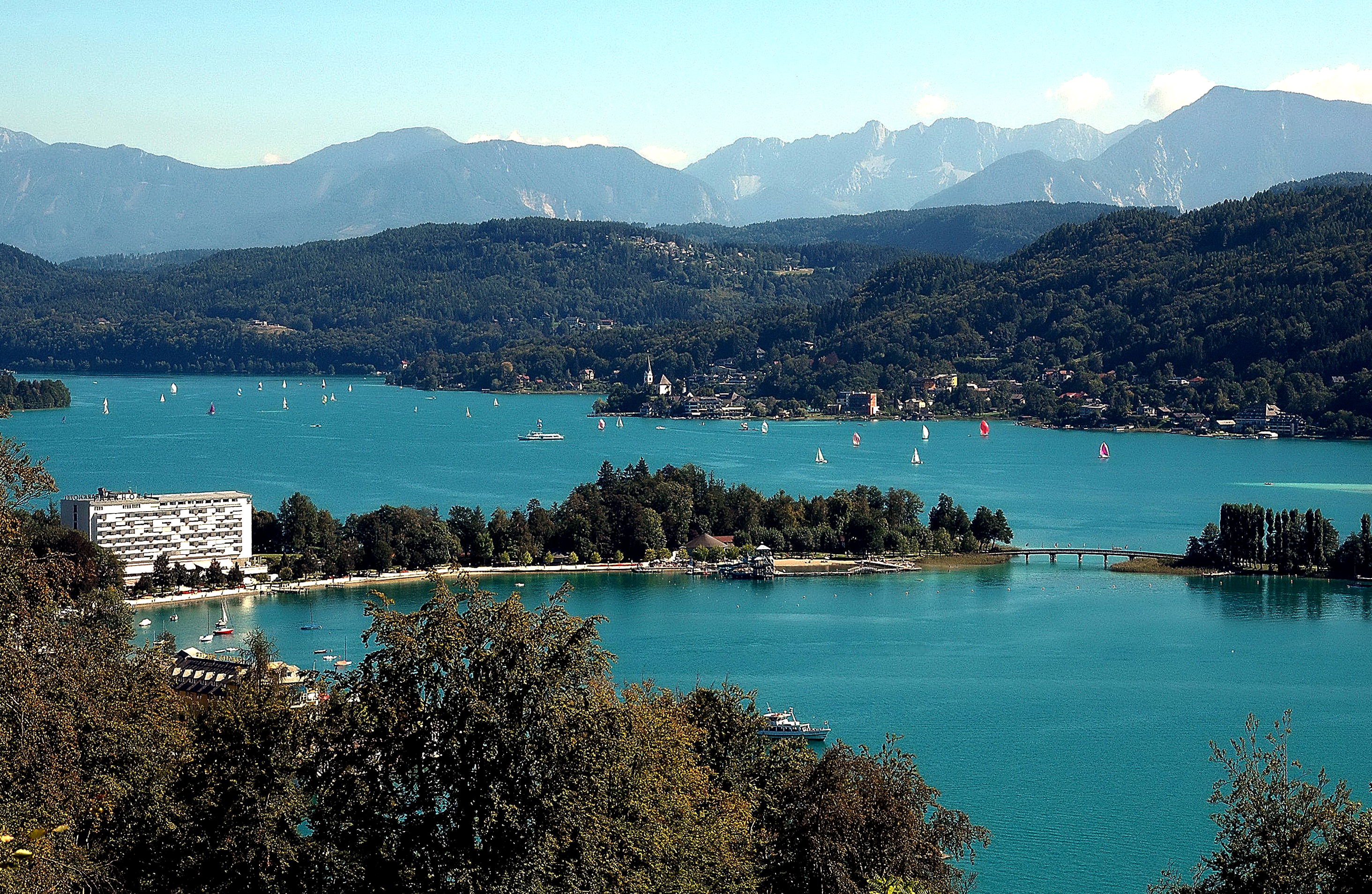 Österreichischer Bergsee mit türkisfarbenem Wasser, Segelbooten und Bergkulisse.